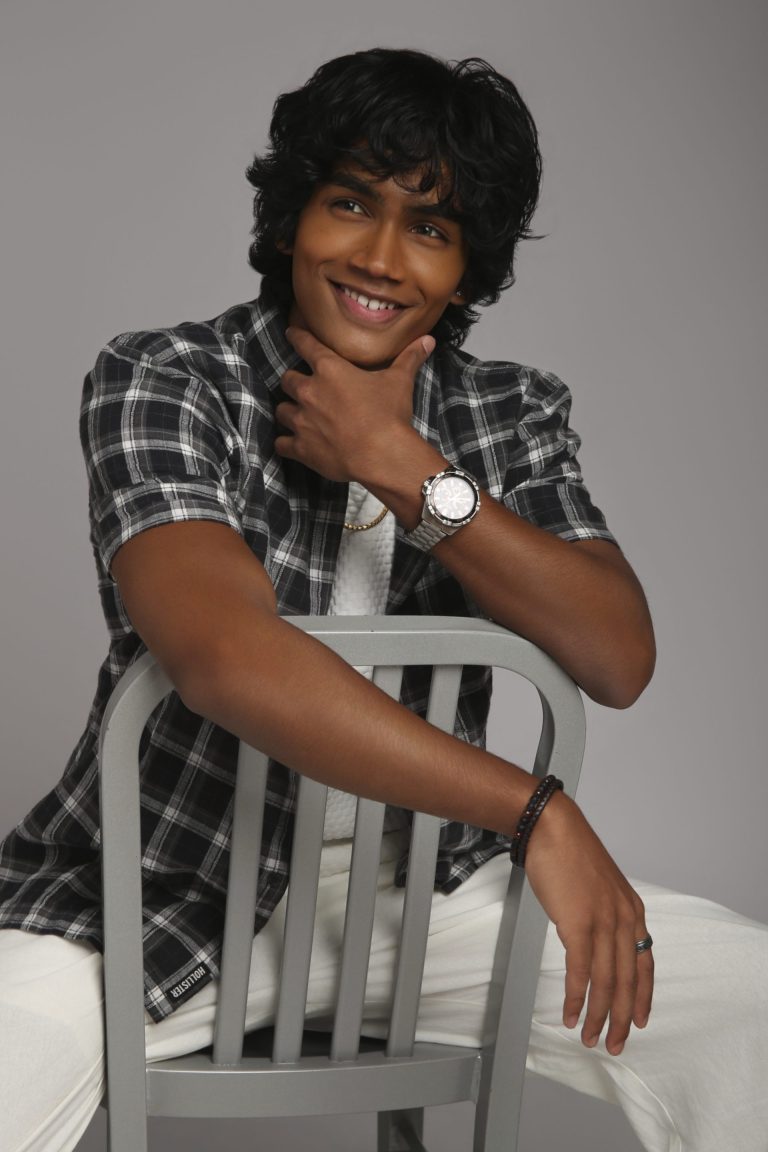 Shabs seated on a chair in a checked shirt